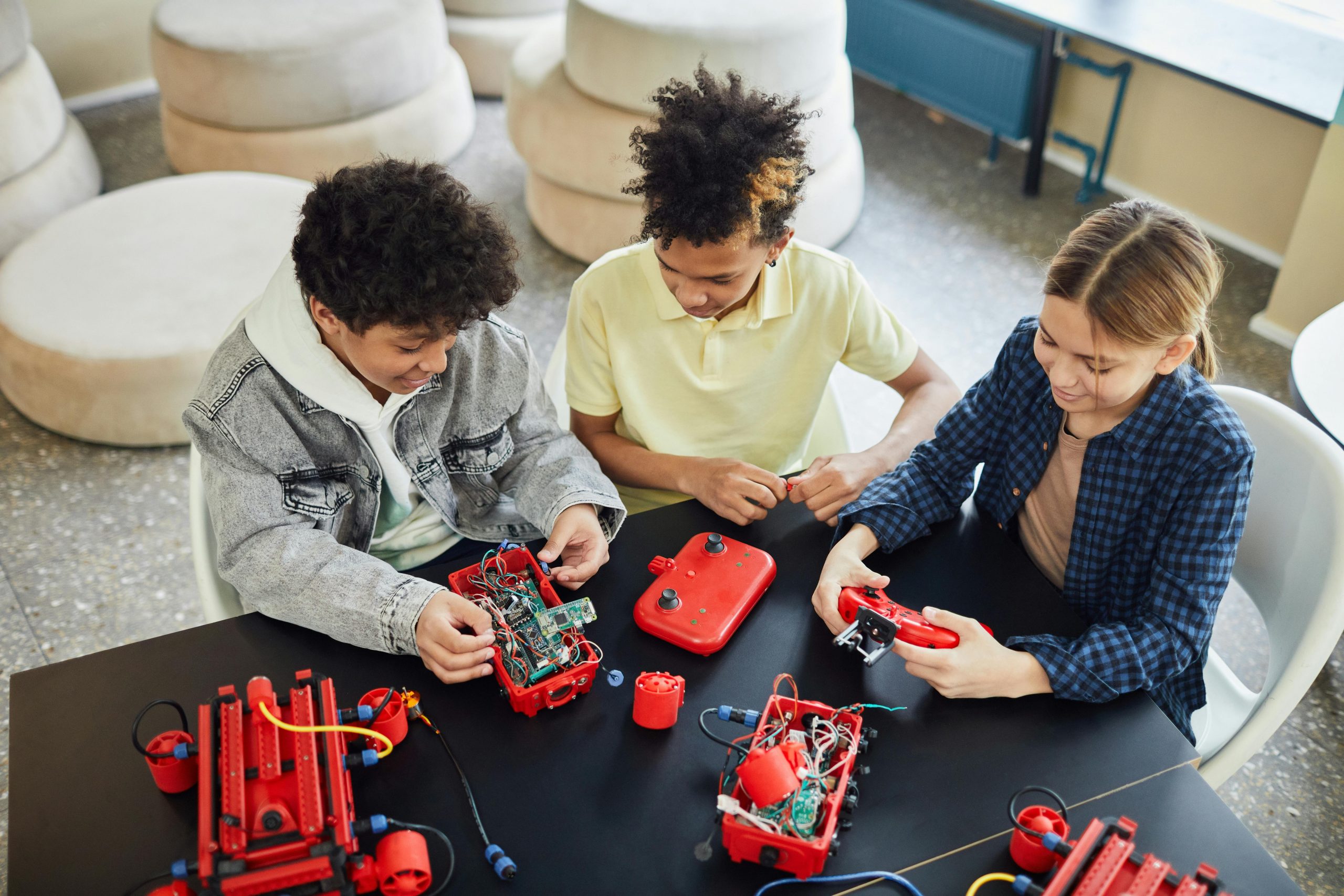 Three children building robots at a table collaboratively, promoting STEM education.